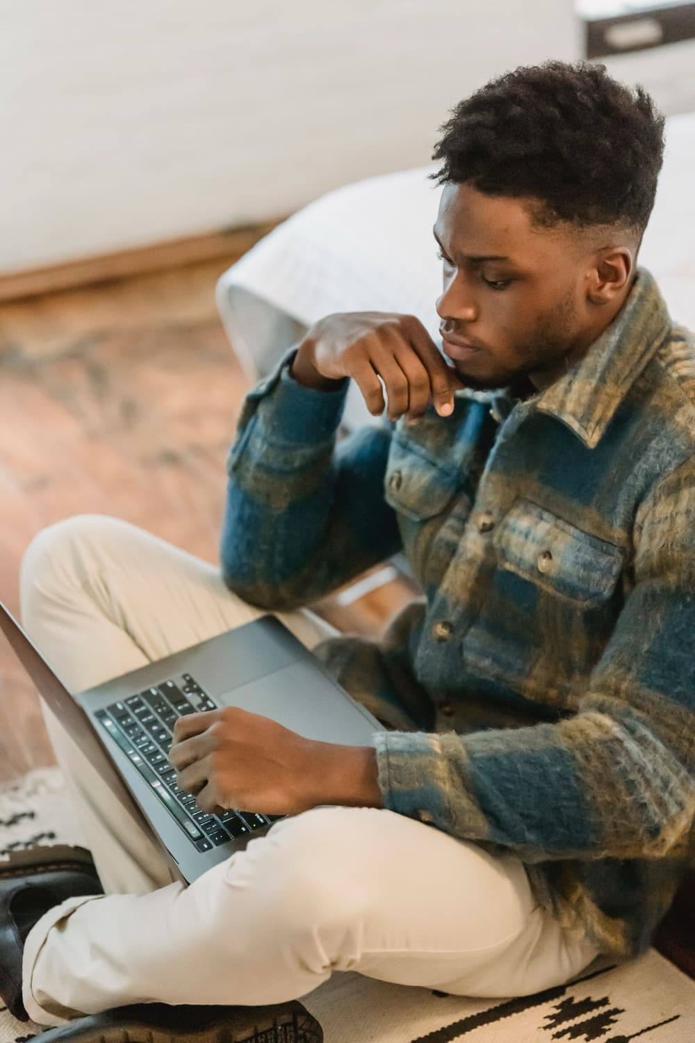 A freelancer working on a laptop on the floor at home